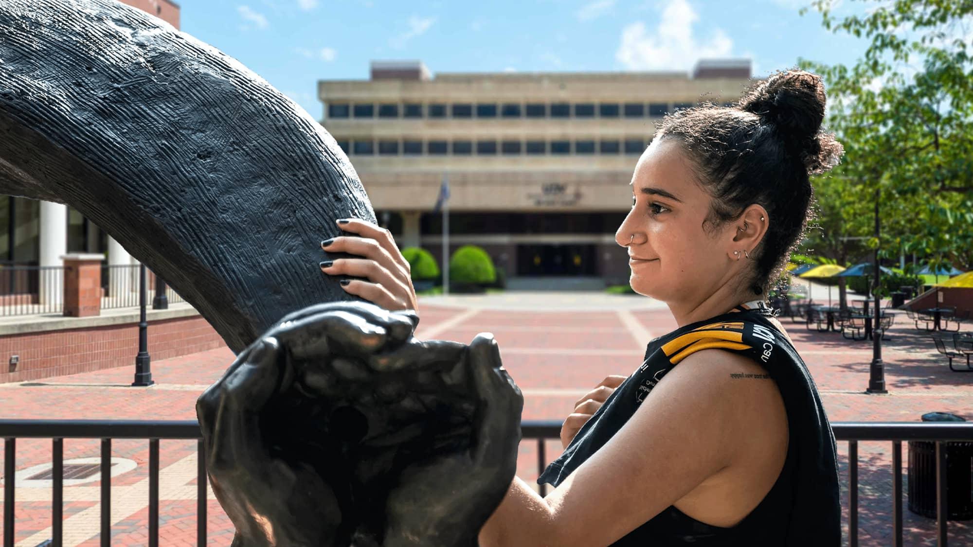 Female VCU student stading by the Rams Horns sculpture outside the The Commons.